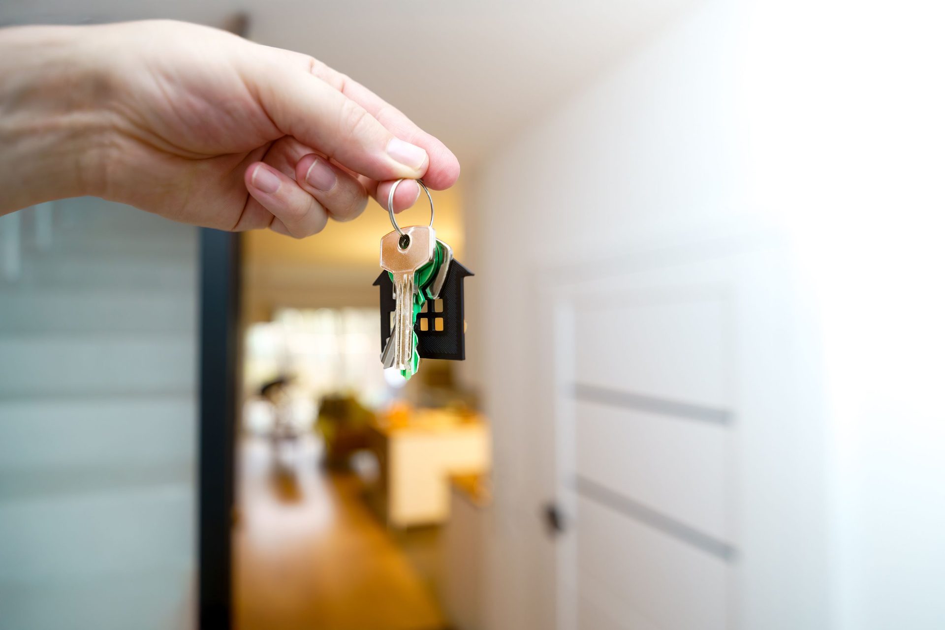 Hand holding a set of house keys in a bright entryway