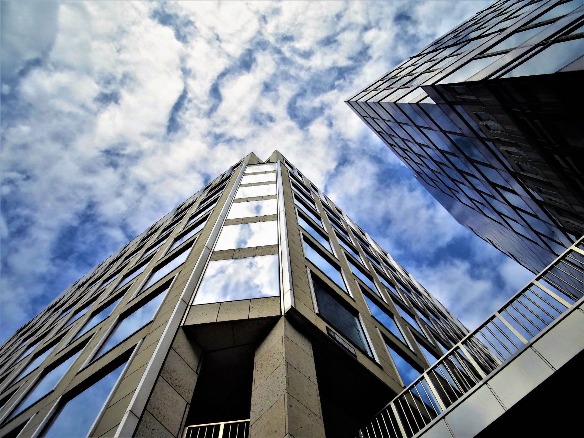 Looking up at glass office towers against a cloudy sky